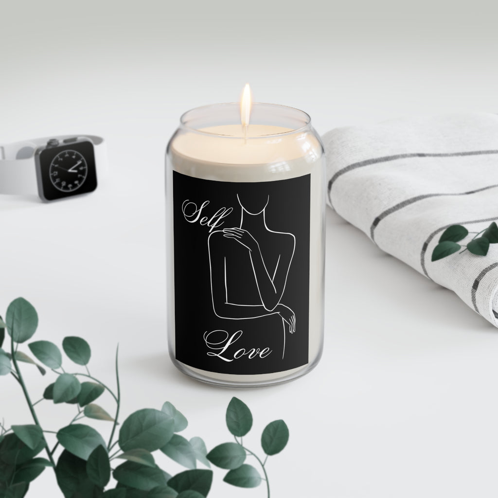 Candle with 'Self Love' label on a white surface with greenery