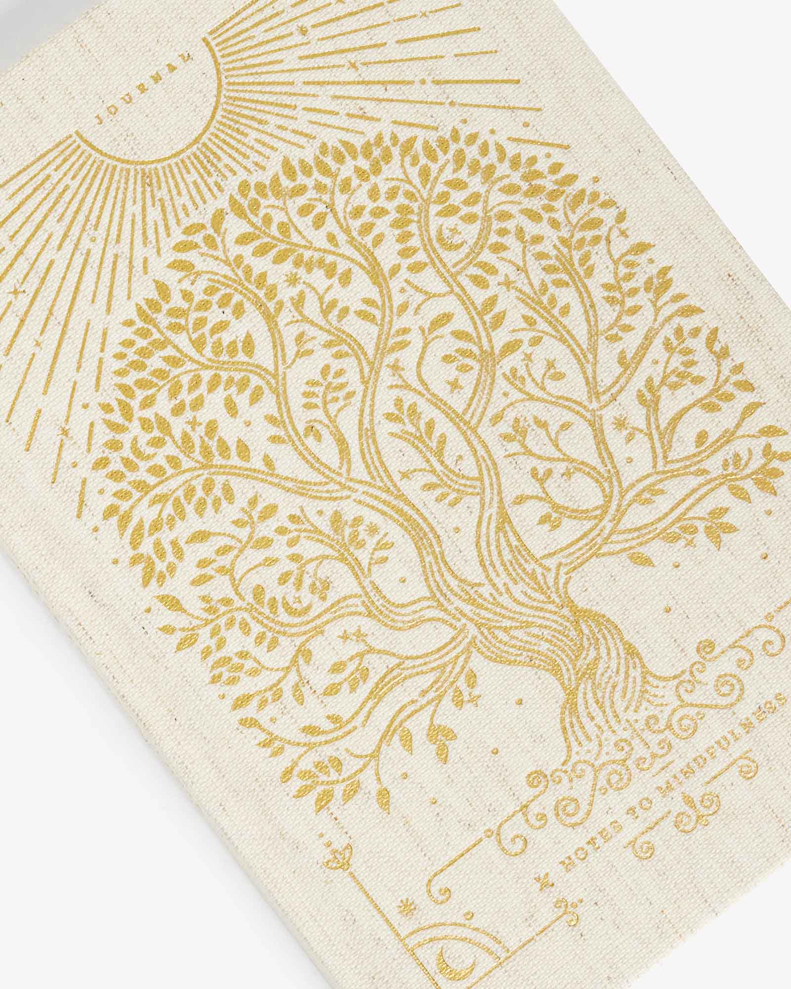Beige notebook with gold tree of life design and text on a white background