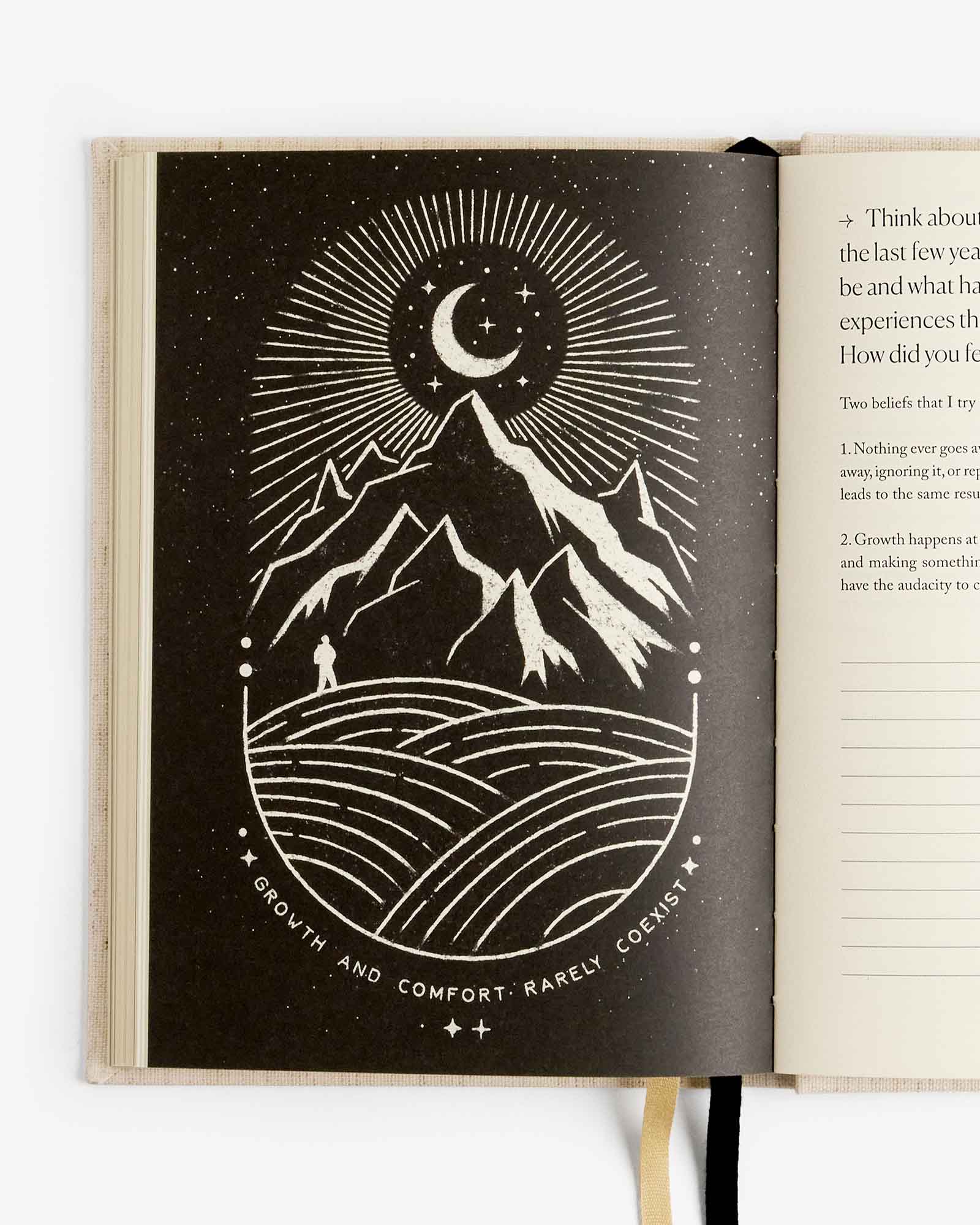 Open book with a black and white illustration of mountains, moon, and person on a white background