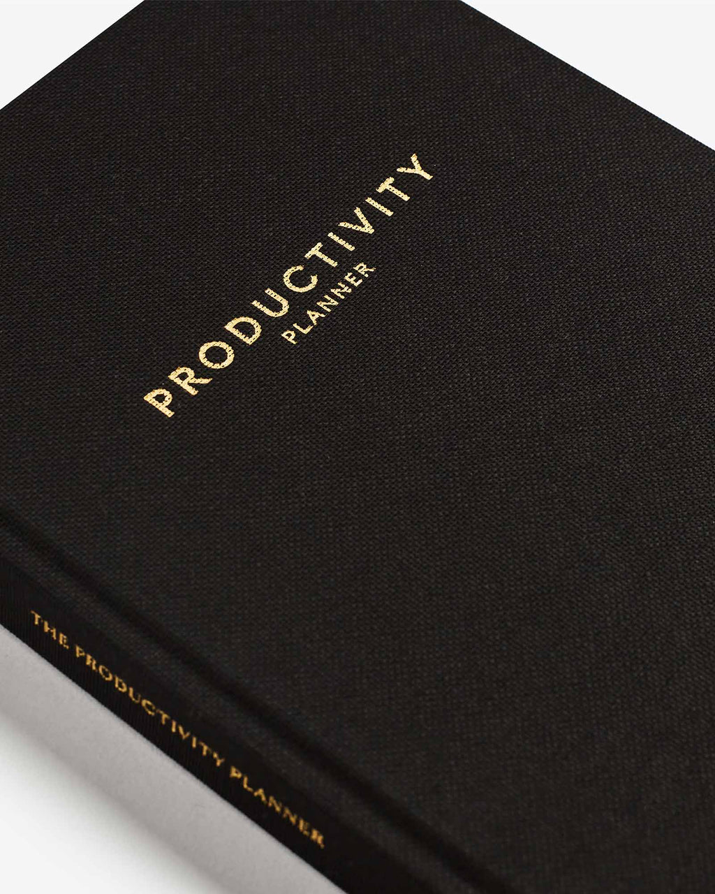 Black productivity planner with gold text on a white background