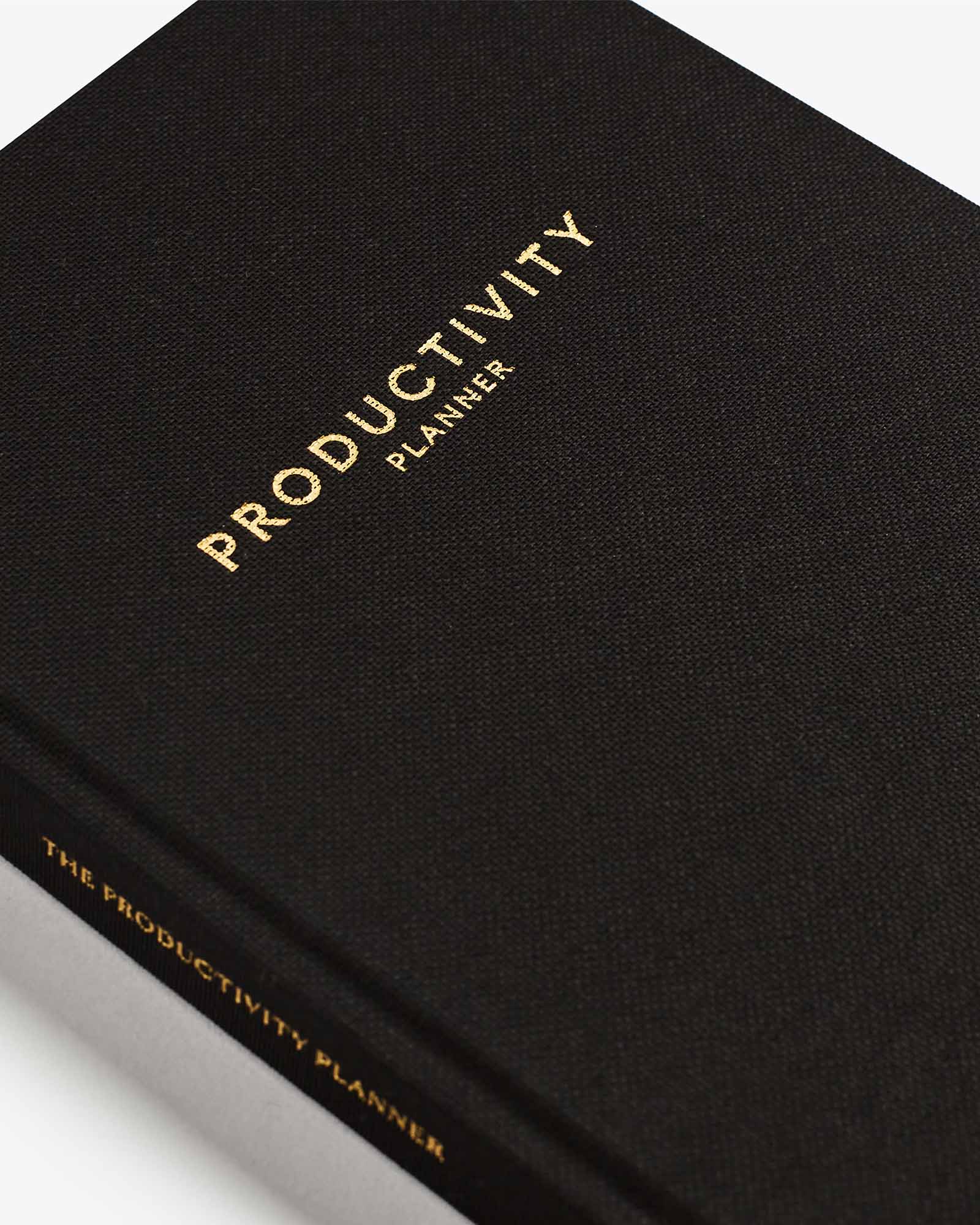 Black productivity planner with gold text on a white background