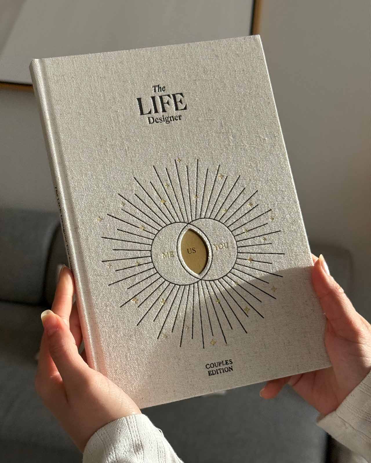 Book titled 'The LIFE Designer' held by a person with a neutral background