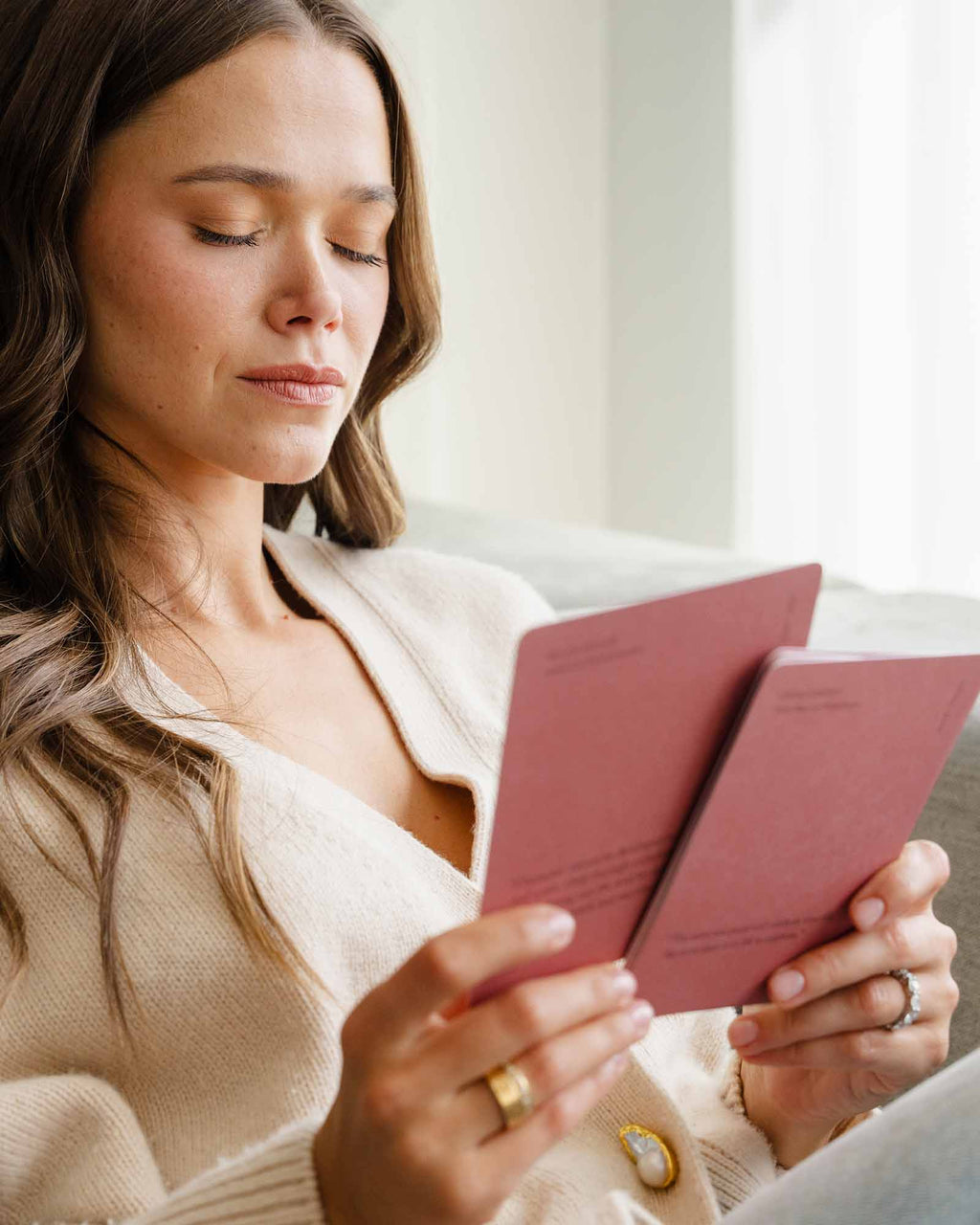 Woman reading a pink book in a softly lit room