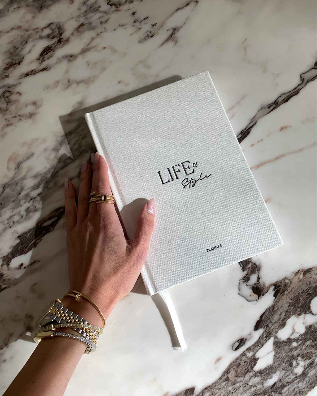 Hand holding a notebook titled 'Life is Simple' on a marble surface