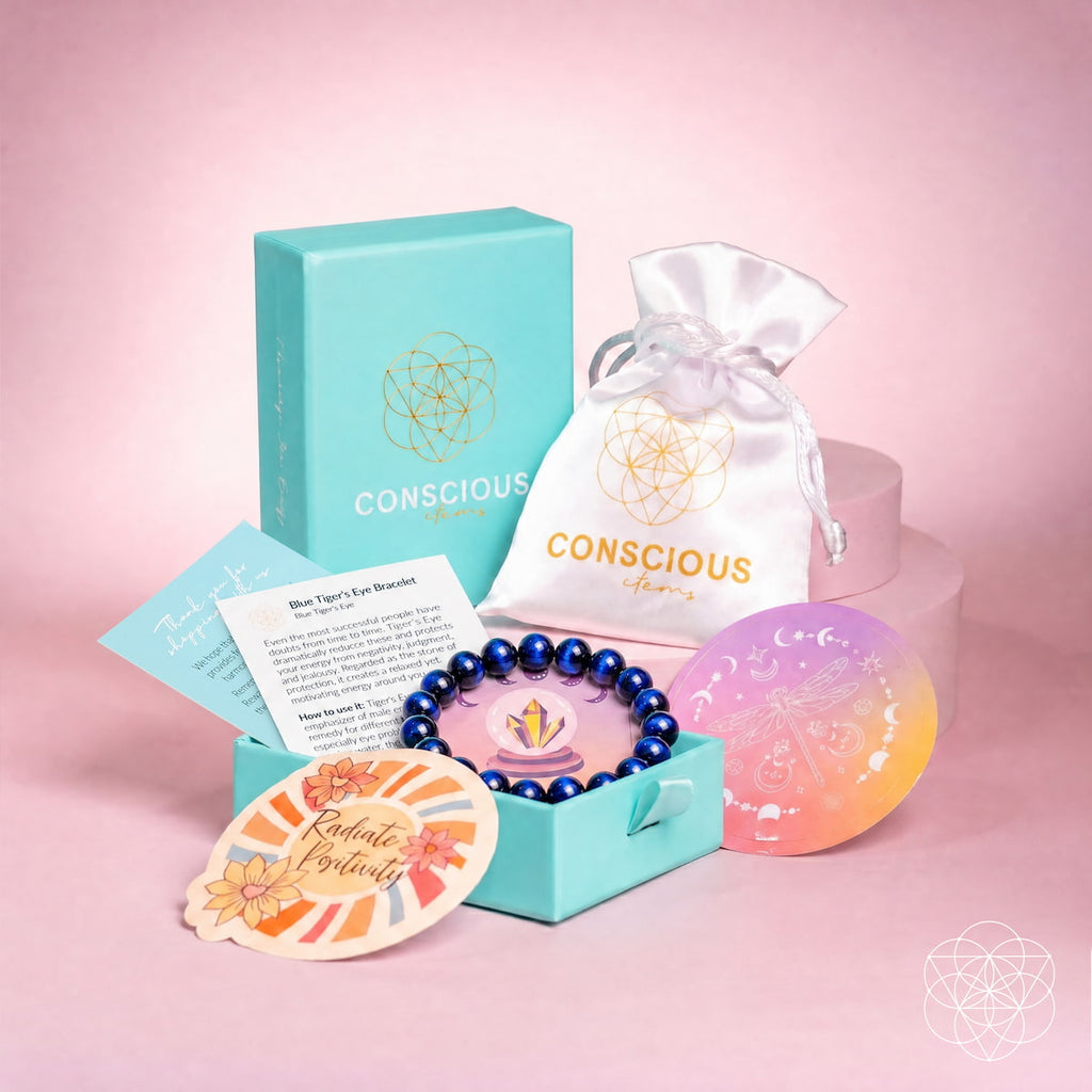 A Conscious Brand gift set arranged on a pink studio background, including a turquoise jewelry box with a blue beaded bracelet, a white satin drawstring pouch, a pastel gradient orb, printed cards, and a matching turquoise box.