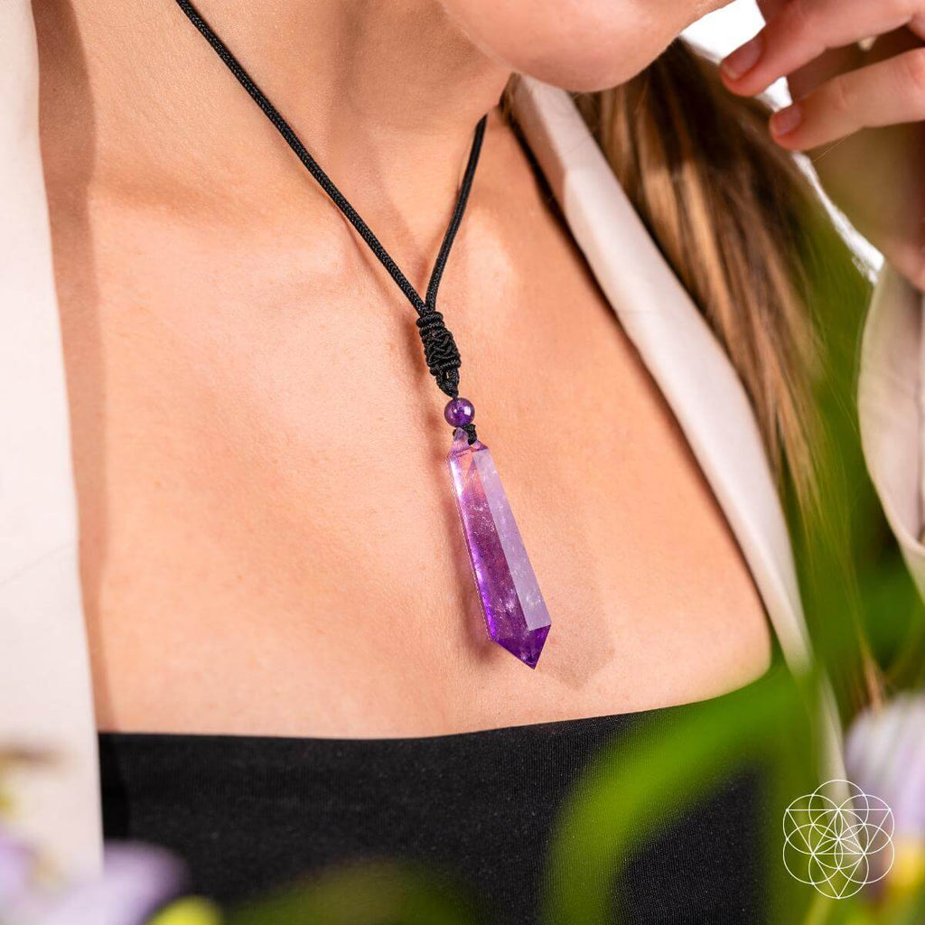 Person wearing a purple crystal necklace with a blurred background