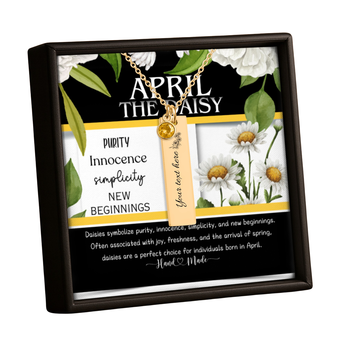 A framed April The Daisy personalized keepsake box containing a gold necklace with a small daisy charm and tag, set against a black background with white daisy illustrations and decorative text.
