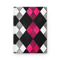 A hardcover notebook with a bold argyle pattern featuring black, white, and textured gray diamonds, accented by bright pink diamonds in the center, shown on a clean white background.
