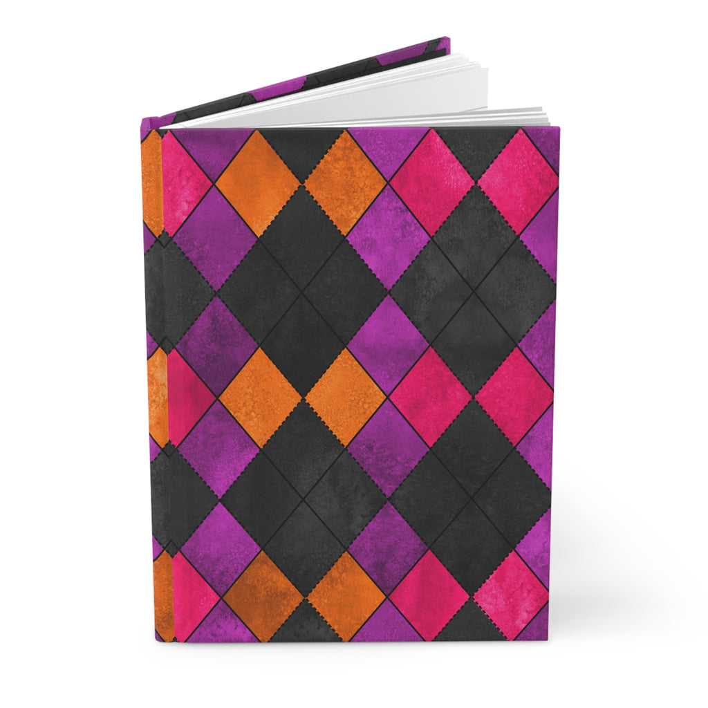 A hardcover notebook with a bold argyle pattern on the cover, featuring alternating black, purple, orange, and pink diamonds, shown on a clean white background.