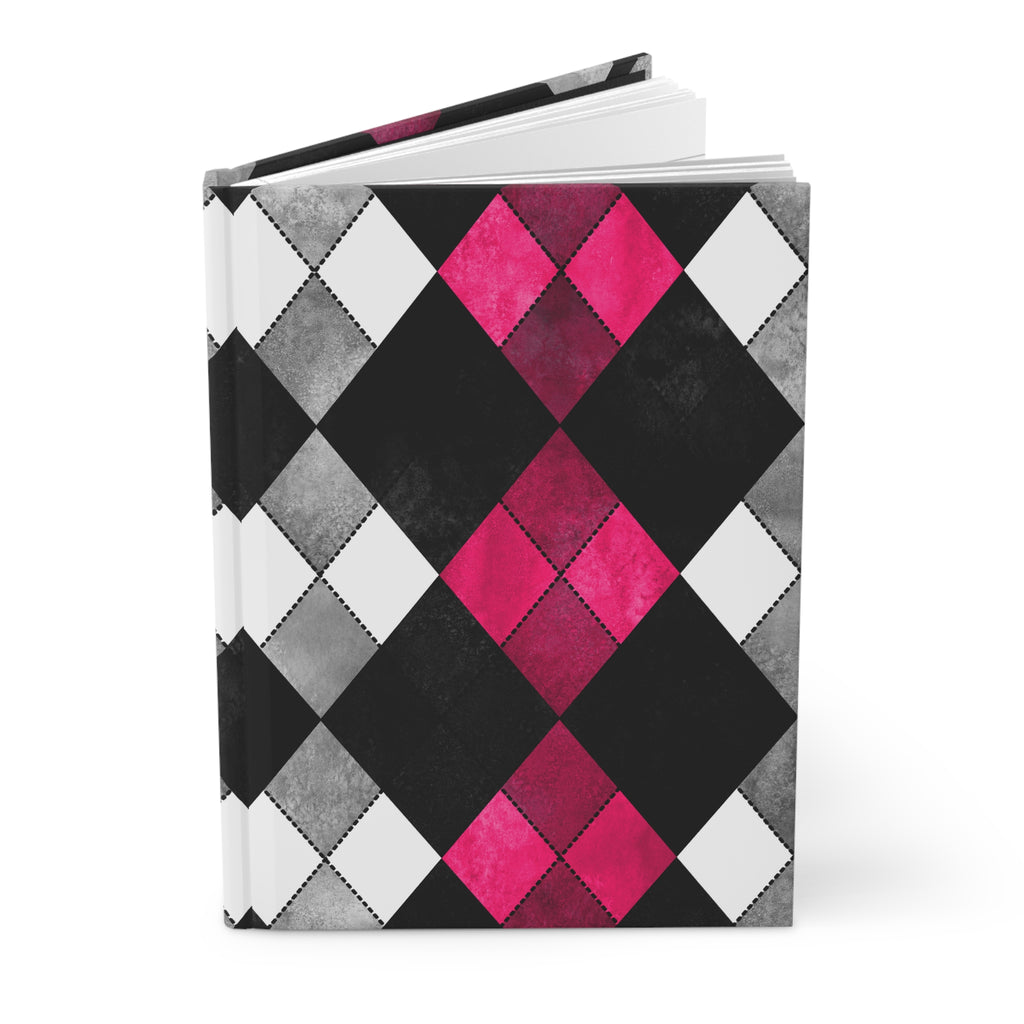 A hardcover notebook with a geometric argyle pattern in black, gray, white, and vibrant hot pink, shown open on a white background.