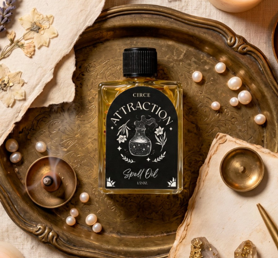 Oil bottle labeled 'Circe Attraction Spell Oil' on a decorative tray with pearls and candles.