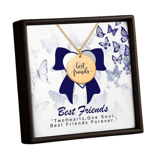 A gold-tone 'best friends' pendant necklace displayed inside a square presentation box with a dark brown frame. The necklace is suspended over a white insert decorated with blue butterflies and a large blue bow, with the text 'Best Friends' and 'TwoHearts, One Soul.