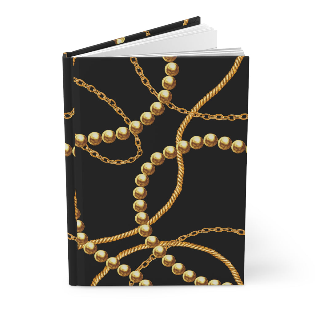 A hardcover notebook with a black cover decorated with a repeating pattern of gold chains and pearl-like beads, shown on a clean white background.