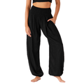 A model wearing black harem-style pants with a smocked elastic waistband, side pockets, and a loose, flowing silhouette, shown against a plain white background.