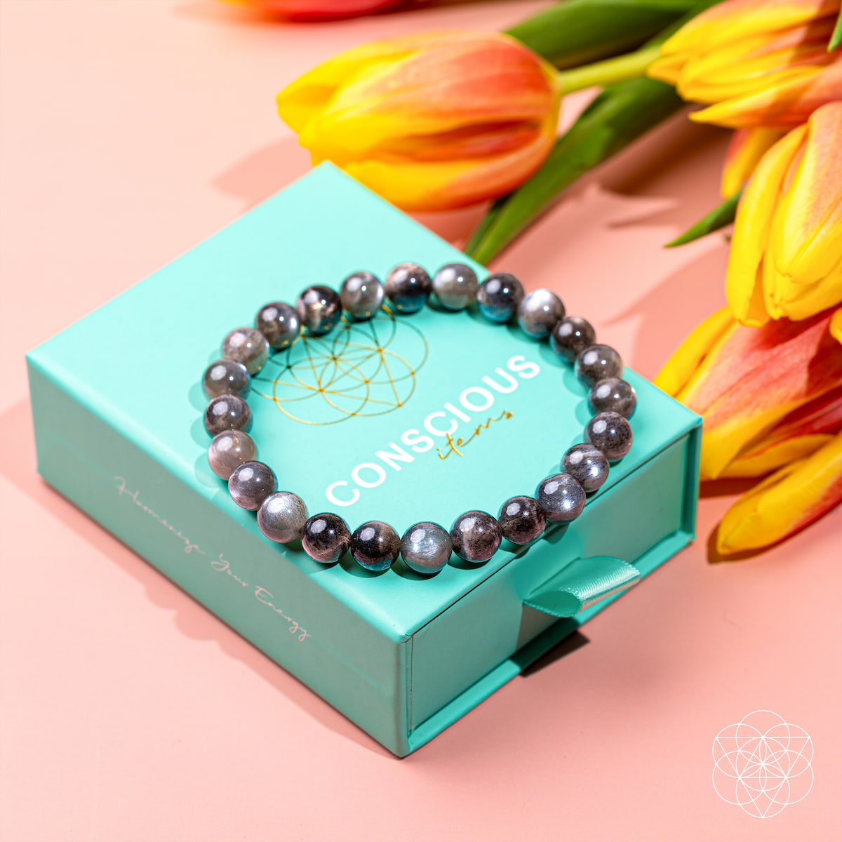 Pearl bracelet on a teal box with tulips in the background