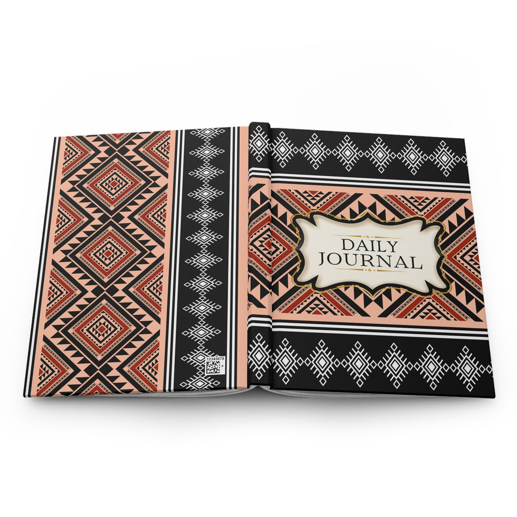 An open daily journal with a geometric tribal pattern cover in black, beige, and terracotta red, featuring a central cream label that reads 'DAILY JOURNAL'.