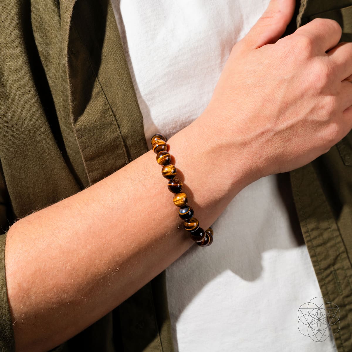 Person wearing a beaded bracelet on their wrist with a neutral background