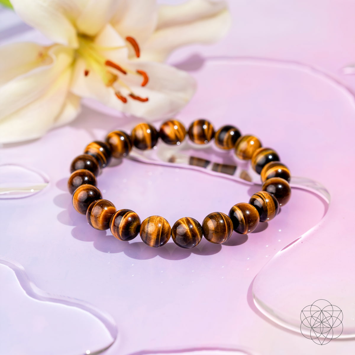 Beaded bracelet with tiger eye stones on a pink surface with a flower in the background