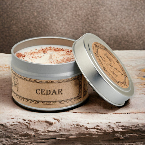 Candle in a tin labeled 'Cedar' on a wooden surface