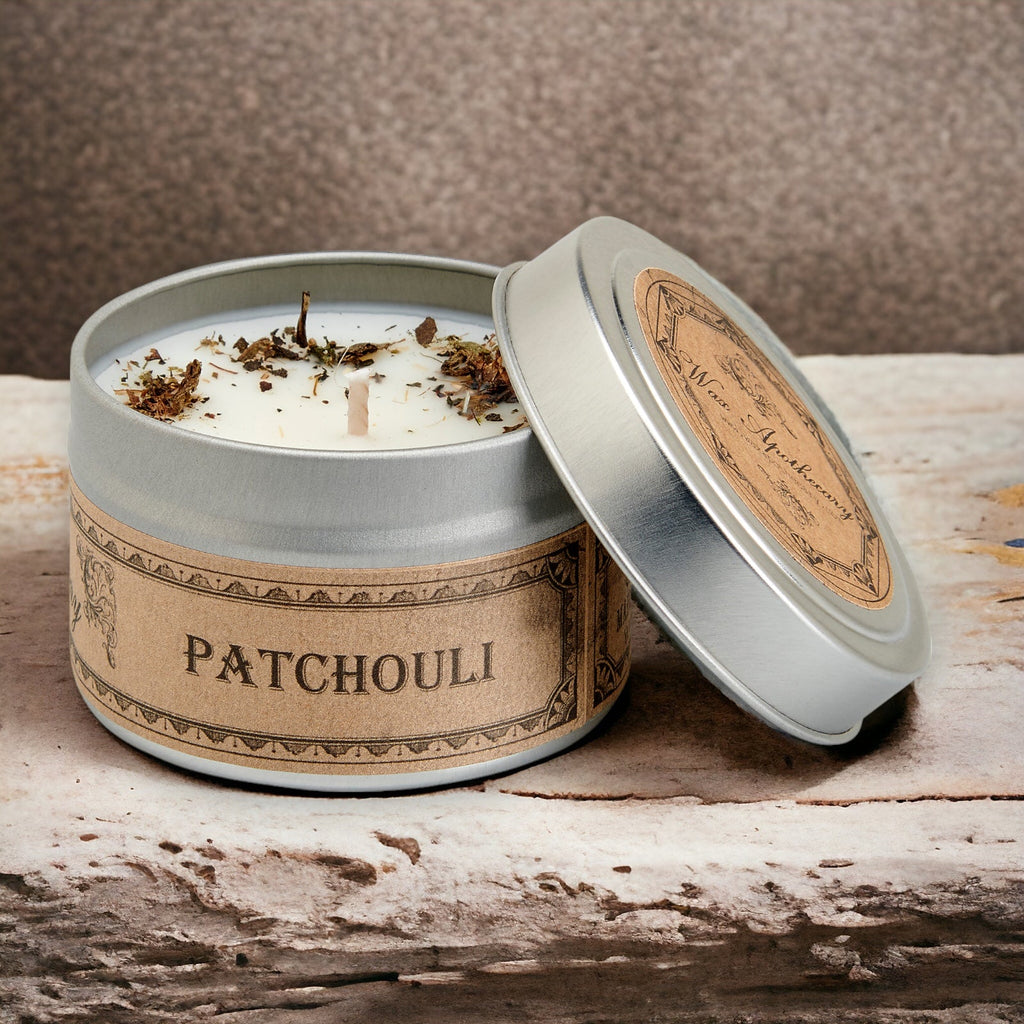 Patchouli candle in a metal tin with a decorative label on a wooden surface.