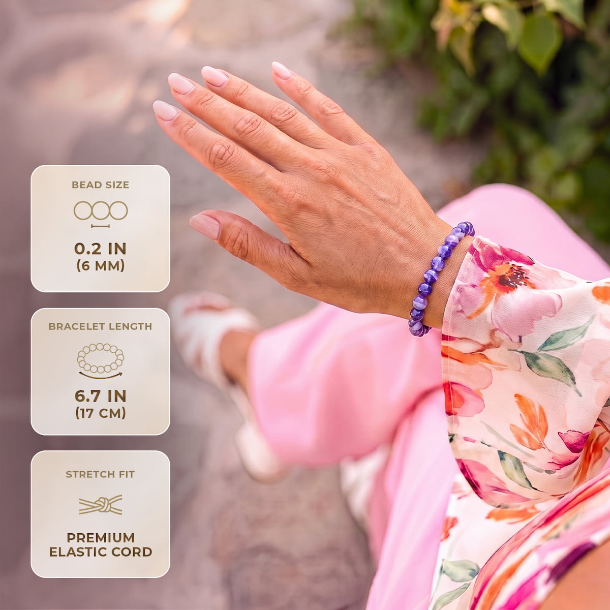 A purple beaded bracelet worn on a woman's wrist, shown in a lifestyle setting with a floral pink dress and outdoor background. Three informational boxes on the left detail the bracelet's bead size (0.