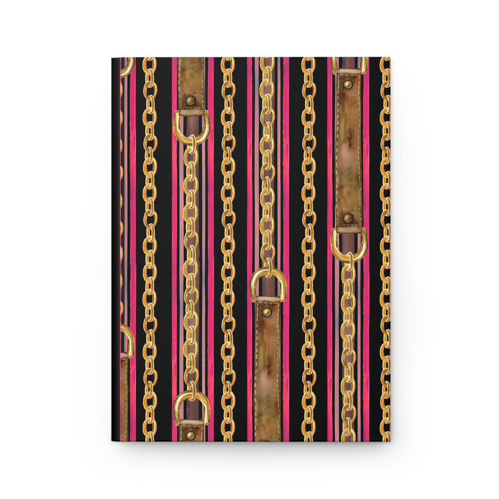 A notebook or journal with a decorative cover pattern featuring vertical gold chains, brown leather-look straps, and pink and black stripes.