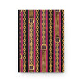 A notebook or journal with a decorative cover pattern featuring vertical gold chains, brown leather-look straps, and pink and black stripes.