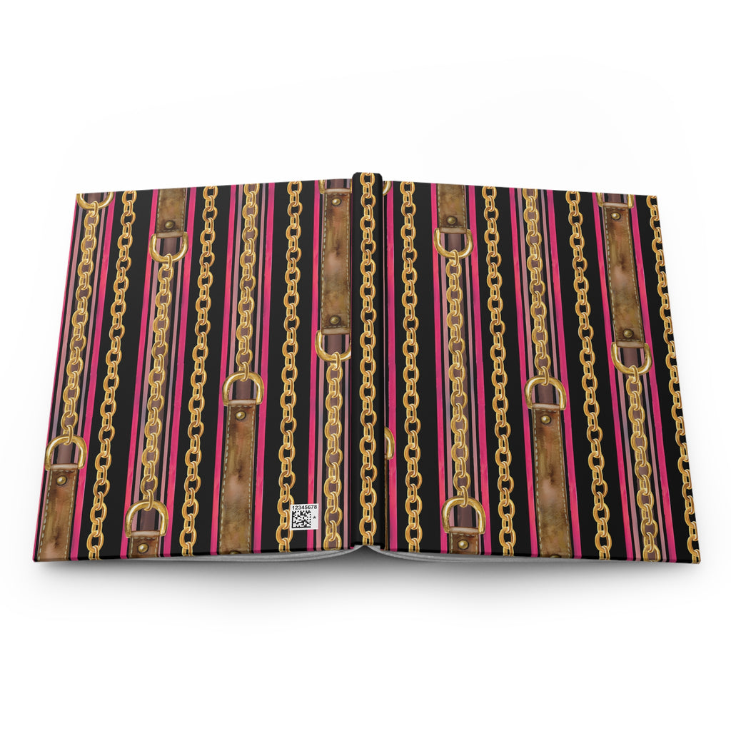 An open book or binder with a decorative cover pattern featuring vertical stripes of gold chains, brown faux-leather straps, and bright pink lines on a black background, photographed on a white studio background.