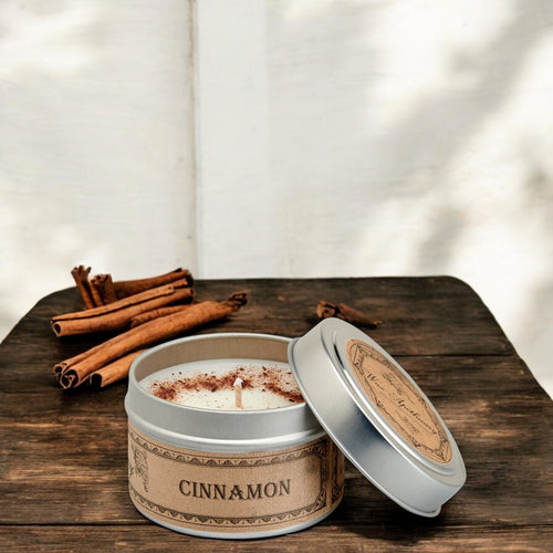 Cinnamon-scented candle in a tin with cinnamon sticks on a wooden surface