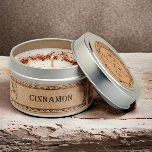 Candle in a tin labeled 'Cinnamon' on a wooden surface