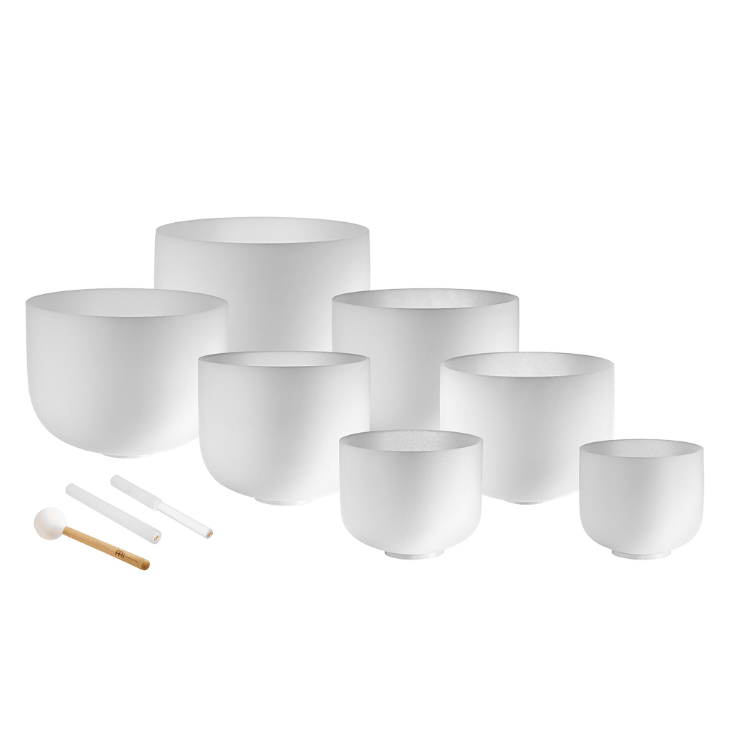 Set of white ceramic singing bowls with accessories on a dark blue background