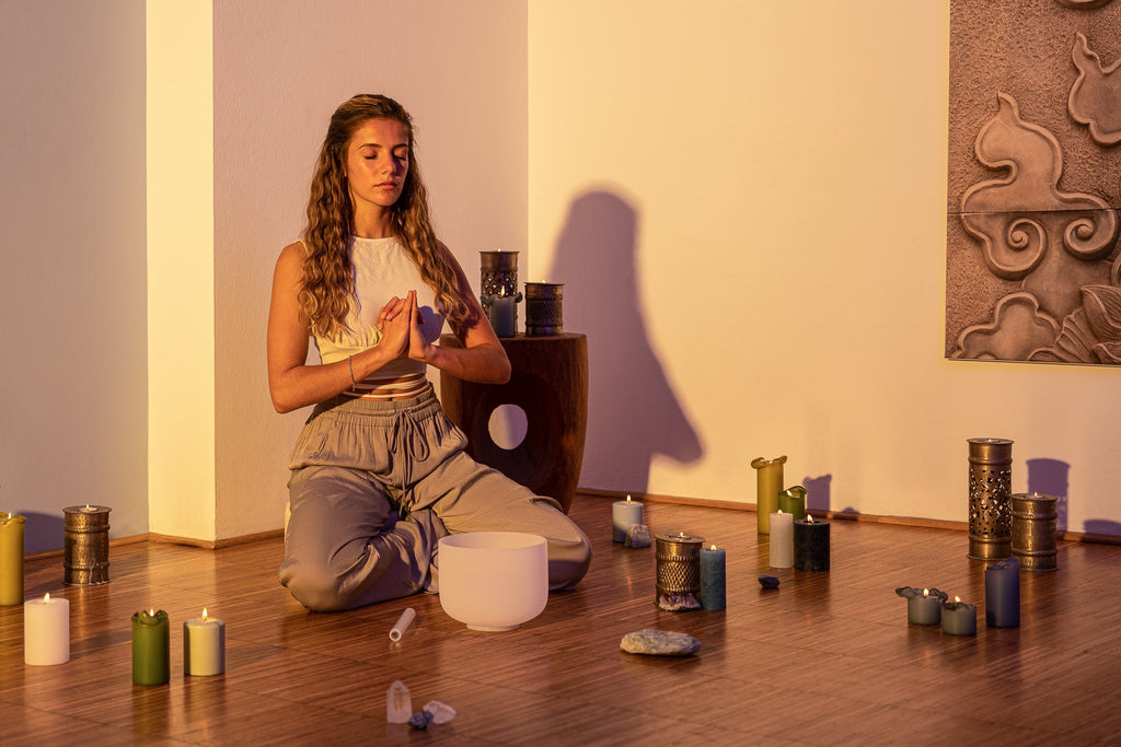Woman meditating in a room with candles and a crystal ball