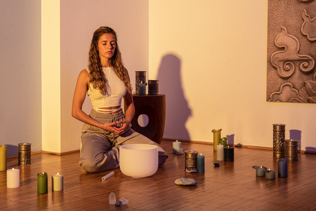 Woman sitting on the floor with a white bowl in a room with candles and incense