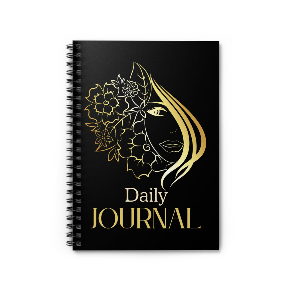 A black spiral-bound daily journal with a gold foil-style illustration of a woman's face surrounded by flowers and the words 'Daily JOURNAL' on the cover, shown on a plain white background.
