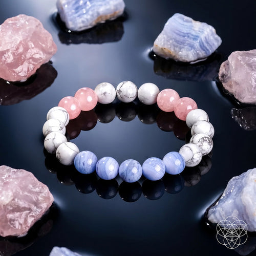 A beaded stretch bracelet made of alternating light pink, lavender-blue, and white/gray marbled beads, displayed on a glossy black reflective surface surrounded by pink and blue crystals.