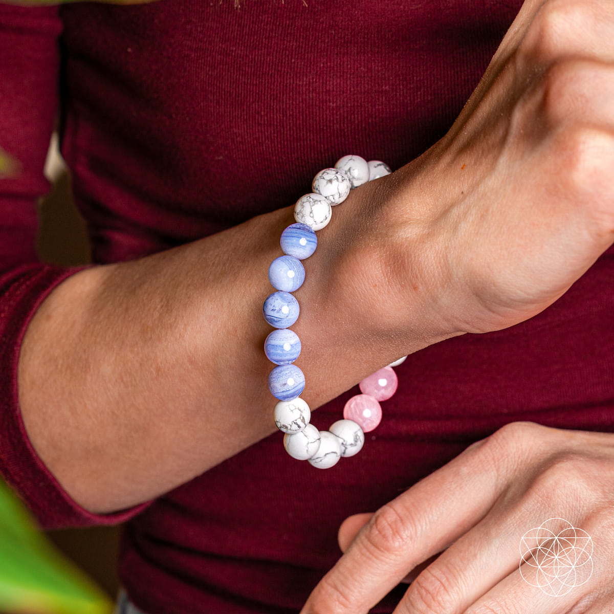 Close-up of a wrist wearing a beaded bracelet with blue, pink, and white beads.