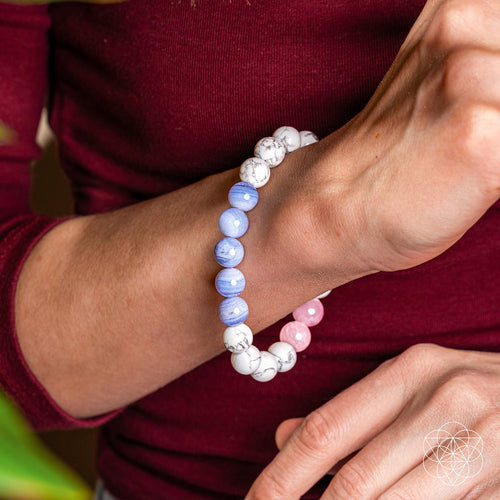 Close-up of a wrist wearing a beaded bracelet with blue, pink, and white beads.