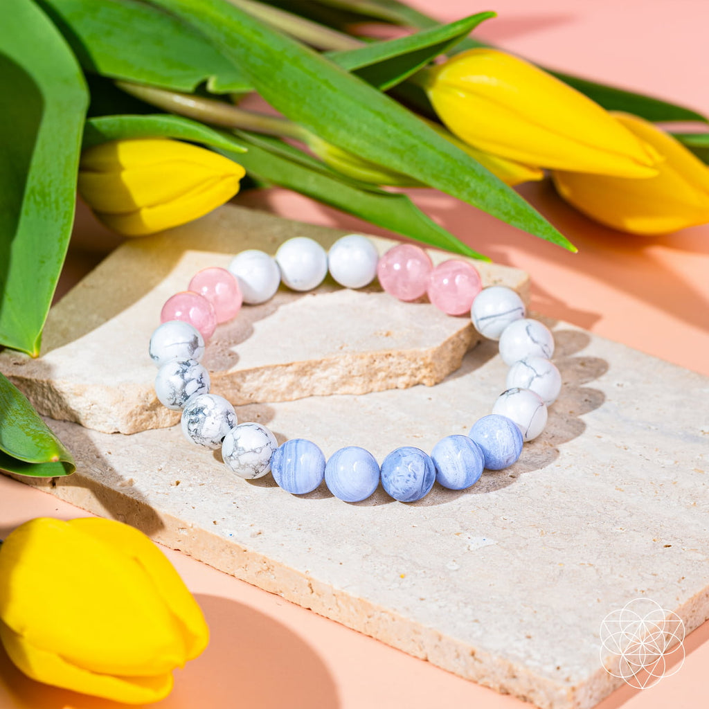 Colorful beaded bracelets on a stone surface with yellow tulips in the background