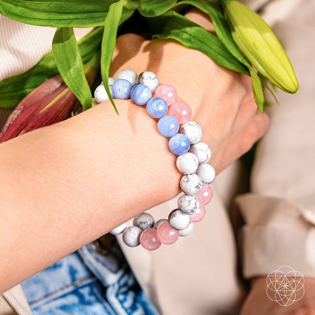 Hand wearing a colorful beaded bracelet holding flowers