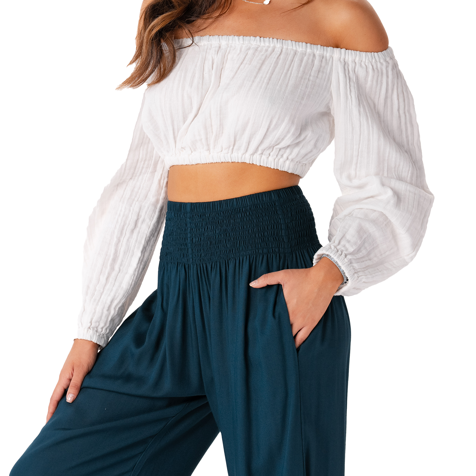 Woman wearing a white off-shoulder top and dark blue pants on a white background