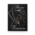 A black hardcover journal with a minimalist white and gold line art illustration of a woman in profile, featuring the words 'Divine Feminine' in elegant script.