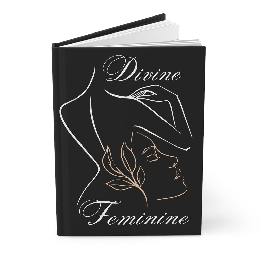 A hardcover journal with a black cover featuring a minimalist line art illustration of a woman in profile, with the words 'Divine Feminine' in white and rose gold script.