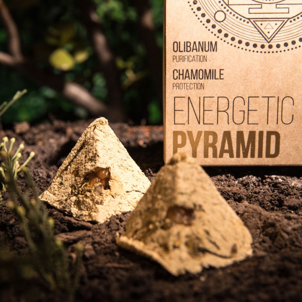 Two sandcastles on a sandy surface with a cardboard box labeled 'Energetic Pyramid' in the background.