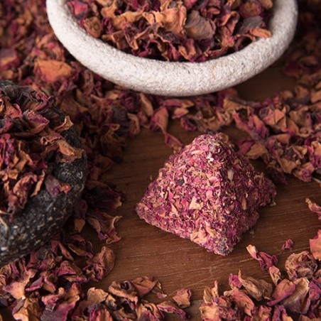 Dried pink and brown herbal tea leaves with a stone bowl on a wooden surface.