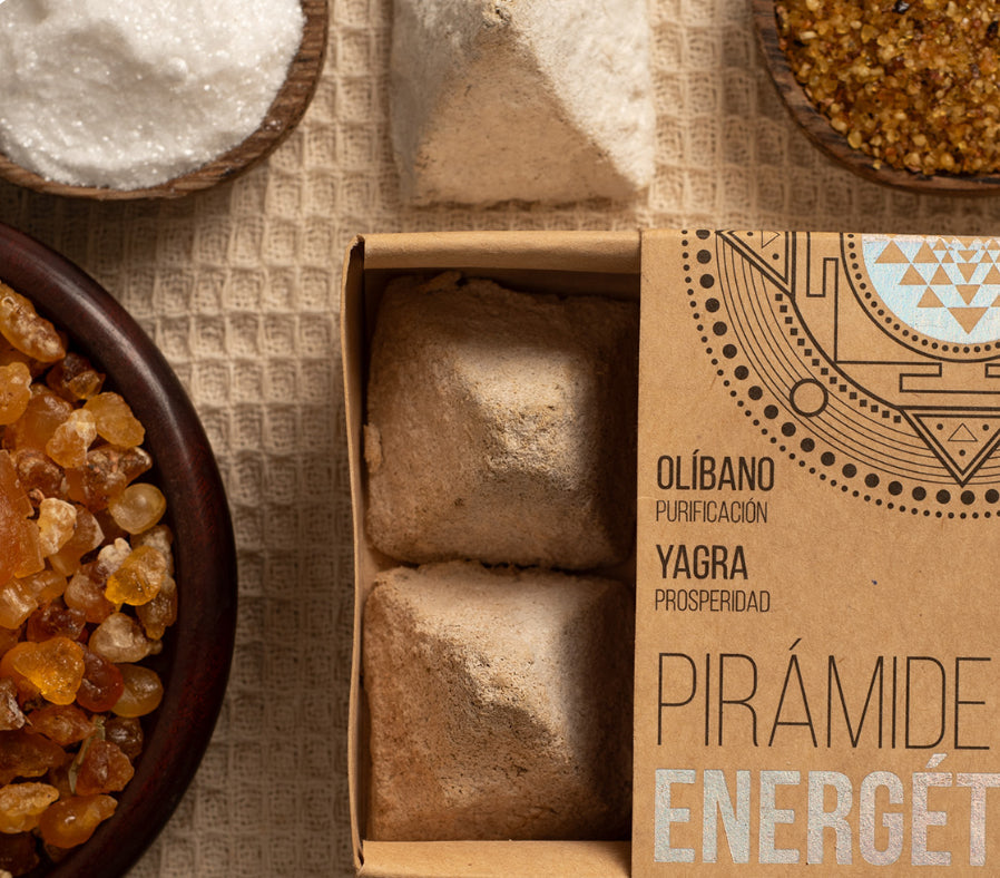Box of pyramid-shaped candies with a decorative label on a textured surface with bowls of ingredients.