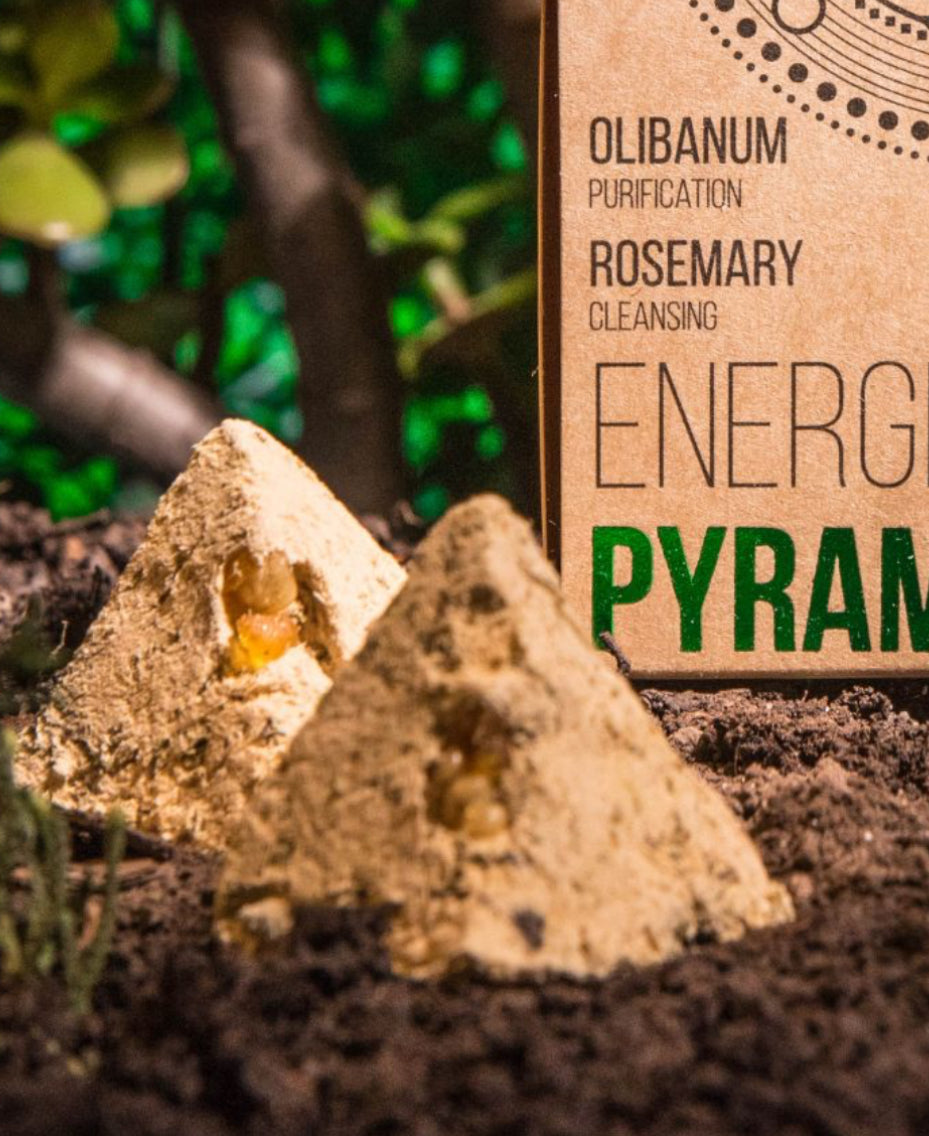 Pyramid-shaped product with a label indicating 'Olibanum', 'Rosemary', and 'Energy' on a natural background.