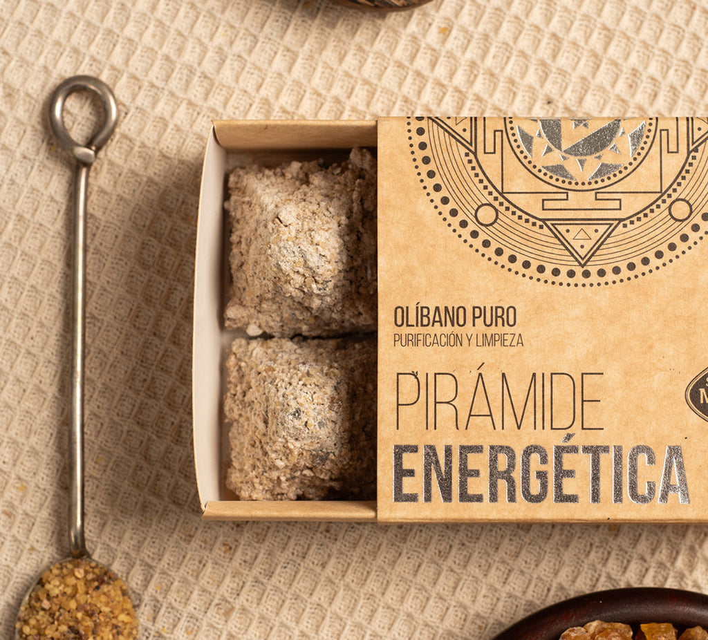 Open box containing pyramid-shaped energy incense with decorative packaging on a textured surface.
