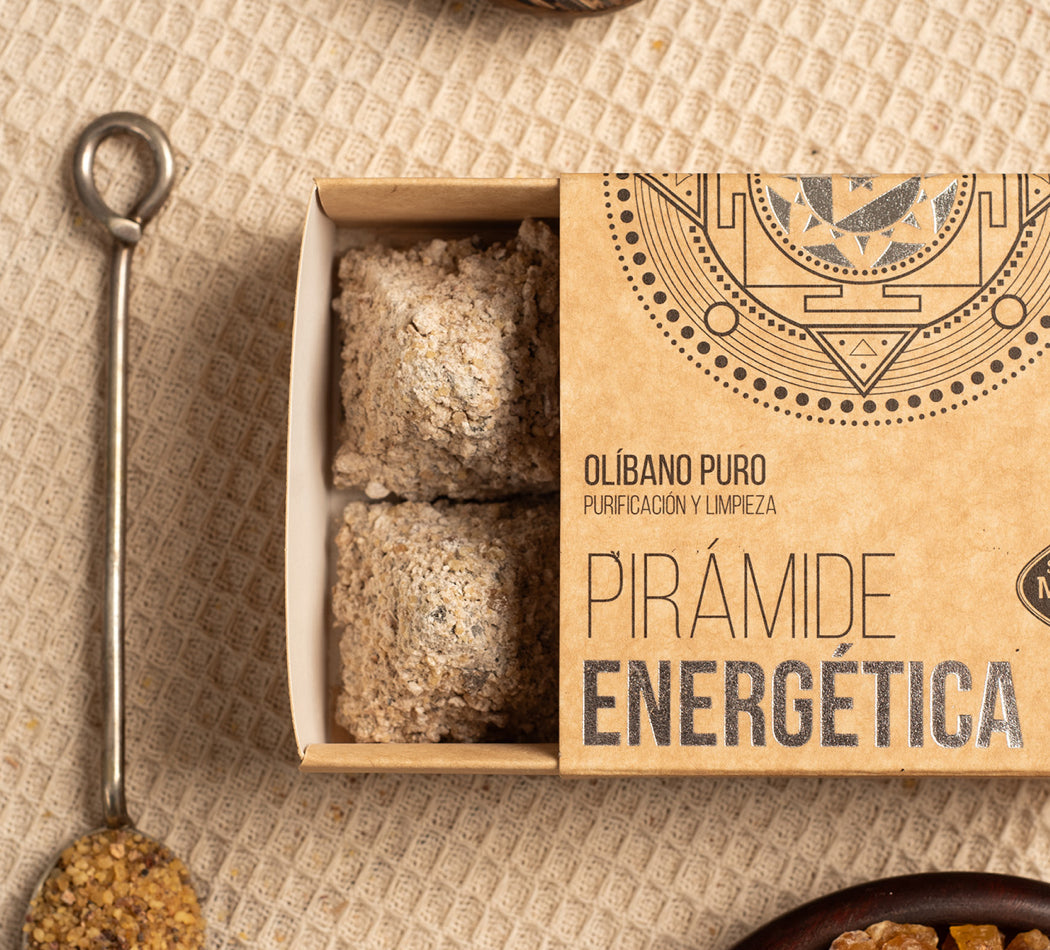 Open box containing pyramid-shaped energy incense with decorative packaging on a textured surface.