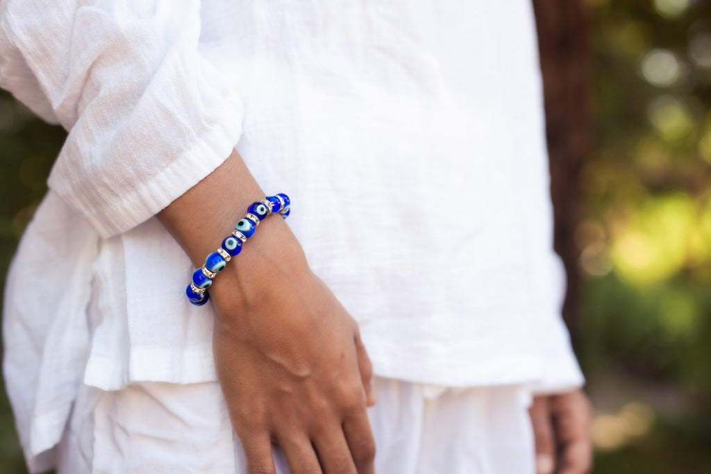 Person wearing a blue beaded bracelet on a blurred natural background