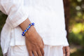 Person wearing a blue beaded bracelet on a blurred natural background